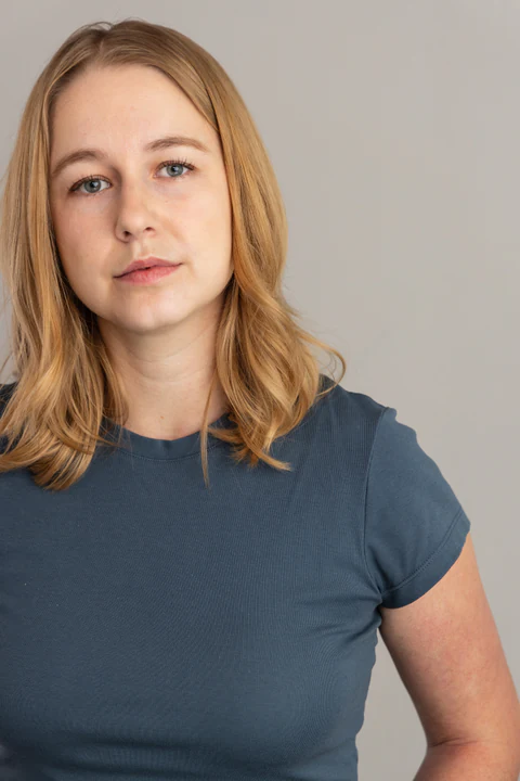 Katie Peabody headshot — slate tee, pale grey background, neutral and direct to camera