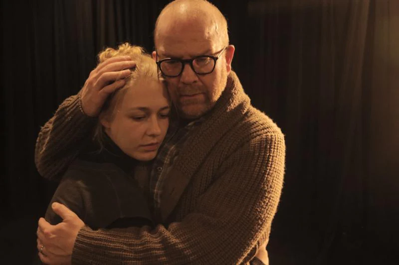 Katie Peabody as Rachel held in an embrace by Fred Cross in the feature film Lear's Shadow, his hand cradling her head, her eyes closed, against a darkened curtain