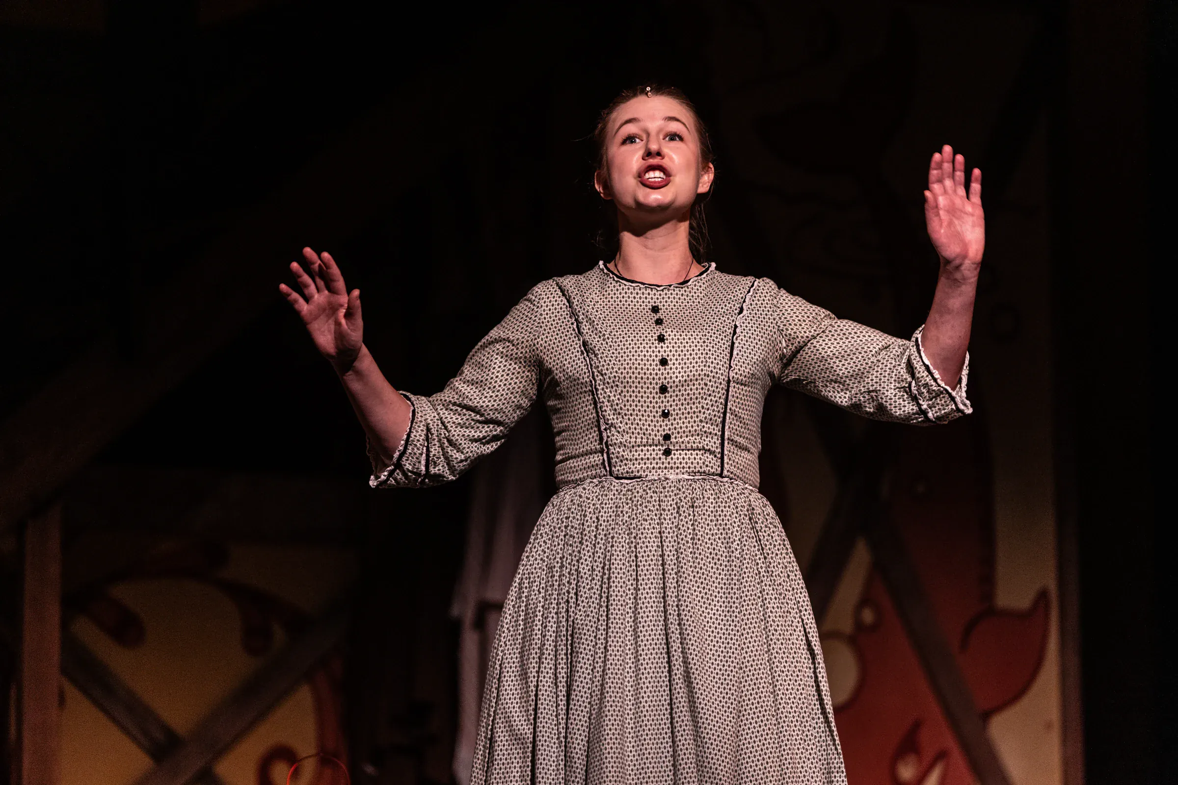 Katie Peabody as Abigail Burgess in Matinicus: A Lighthouse Play at Penobscot Theater Company, arms raised mid-speech on a darkened stage
