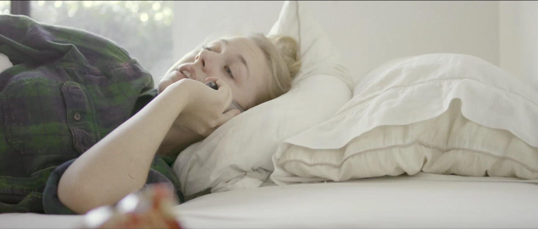 Katie Peabody as Casey lying in bed in soft daylight, from the short film Natural Disasters