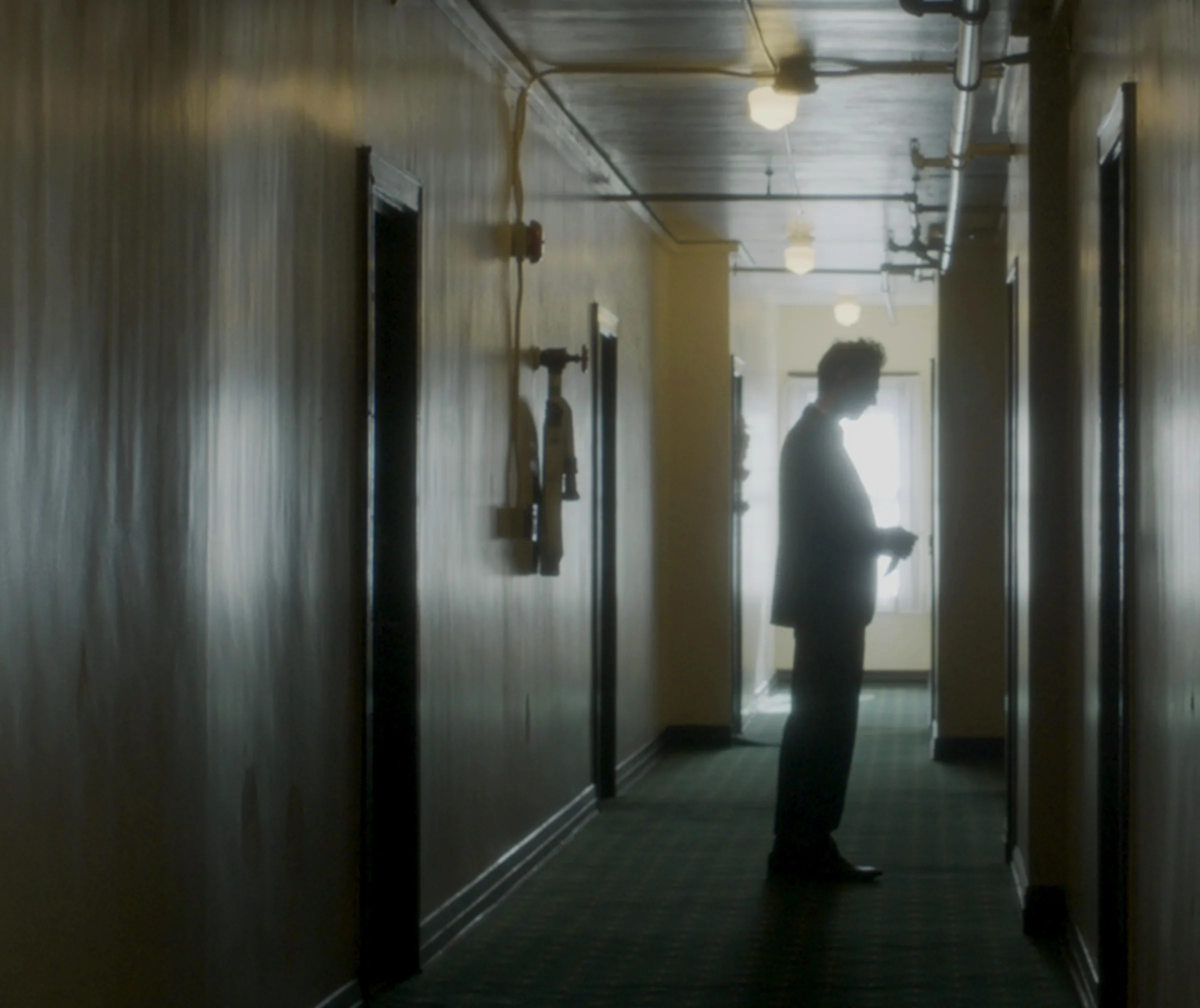 A figure alone at the end of a dim corridor, from Remnants, in which Katie Peabody voices Emma