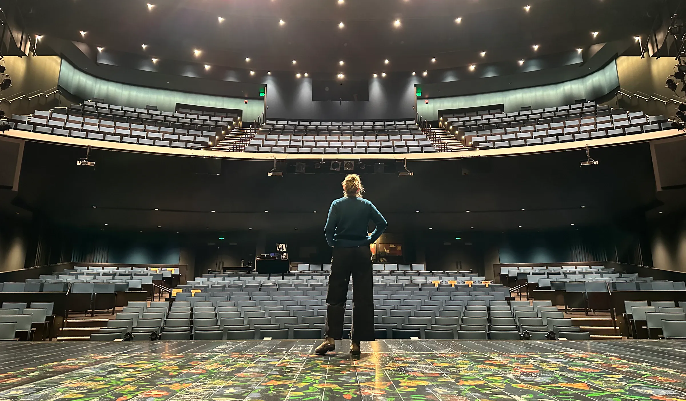 Katie Peabody standing on the Seattle Repertory Theater stage, facing the empty house
