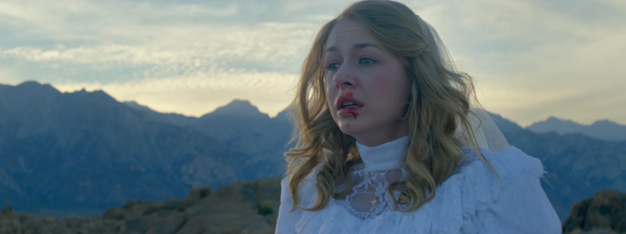 Katie Peabody as Young Lilly in the feature film Straight On Till Morning, in a white dress against a mountain sky