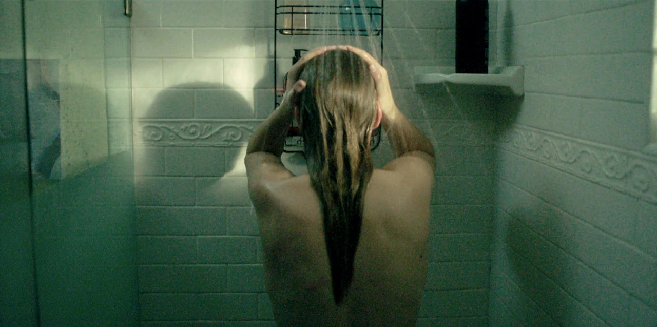 Katie Peabody as Meg in the short film Watermark, seen from behind in a tiled shower, hair wet